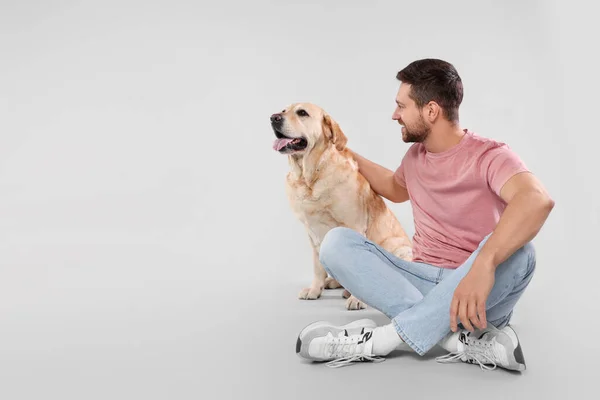 愛らしいラブラドールを持つ男ライトグレーの背景 テキストのためのスペースに犬を取得します 可愛いペット — ストック写真