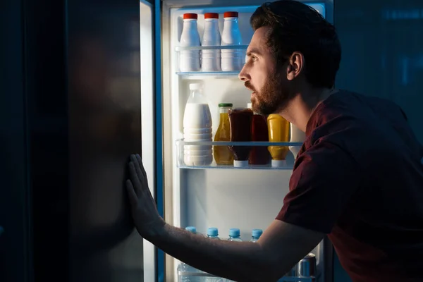 男人在晚上从厨房的冰箱里挑食 坏习惯 — 图库照片