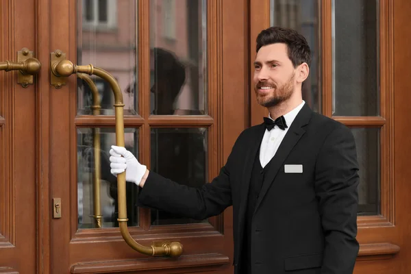 エレガントなスーツと白い手袋のバトラー木製のホテルのドアを開く — ストック写真