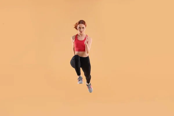 Mujer Joven Ropa Deportiva Saltando Sobre Fondo Beige —  Fotos de Stock