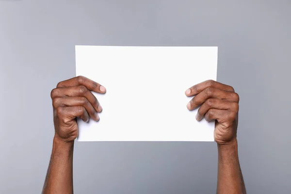 African American Man Holding Sheet Paper Grey Background Closeup Mockup — Fotografia de Stock