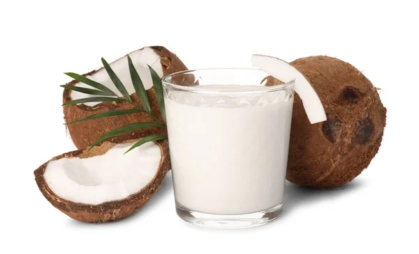 おいしいビーガンミルクのガラス 白の背景にココナッツと緑の葉 — ストック写真
