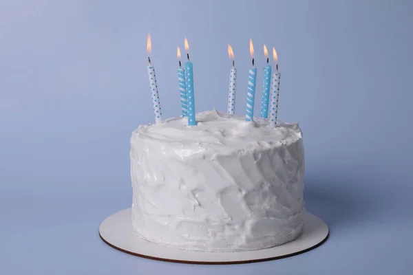 stock image Delicious cake with cream and burning candles on light blue background