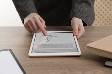 Elektronik imza. Ahşap masada tablet kullanan kadın, yakın plan.