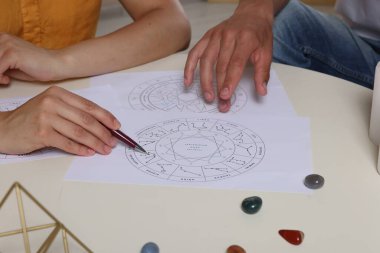 Astrolog masadaki istemciye natal çizelgeleri gösteriyor, yakın plan