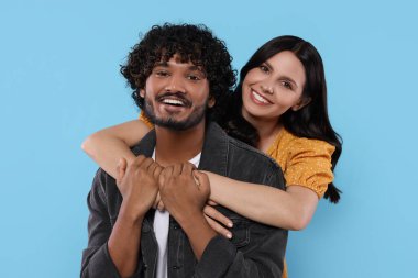 Uluslararası randevu. Mutlu çift açık mavi arka planda sarılıyor.