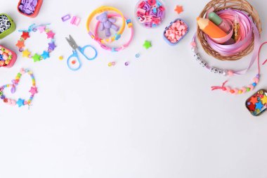 Çocuğun el yapımı boncuklu mücevherleri ve beyaz arka planda farklı malzemeler. Metin için boşluk