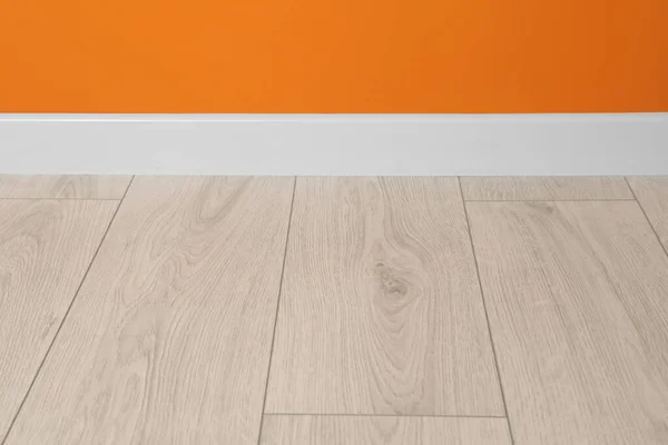 Witte Plint Gelamineerde Vloer Bij Oranje Wand Binnenshuis — Stockfoto