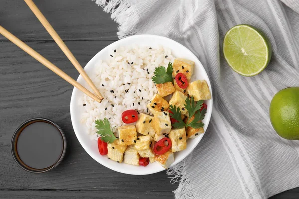 stock image Delicious rice with fried tofu, chili pepper and parsley served on grey wooden table, flat lay