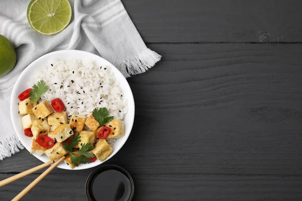 stock image Delicious rice with fried tofu, chili pepper and parsley served on grey wooden table, flat lay. Space for text