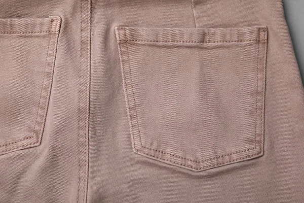 带灰色背景口袋的米色牛仔裤 — 图库照片
