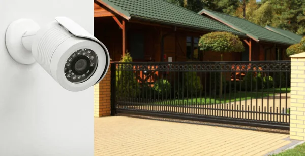 Home security camera on wall against houses on street, closeup