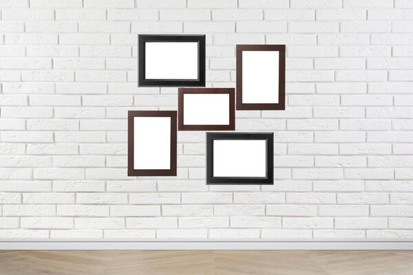 Blank wooden frames hanging on white brick wall. Mockup for design