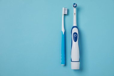 Elektrik ve plastik diş fırçaları turkuaz arka planda, düz yerde. Metin için boşluk