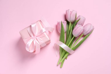 Pembe arka planda fiyonklu ve laleli güzel hediye kutusu, düz yatıyordu.