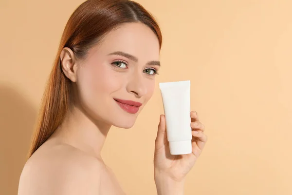 stock image Beautiful young woman holding sun protection cream on beige background, space for text