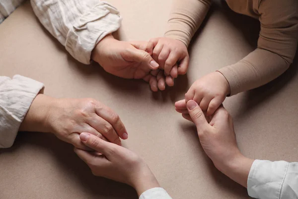 Family holding hands together on brown background, above view
