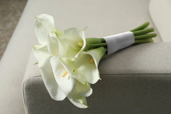 stock image Beautiful calla lily flowers tied with ribbon on sofa indoors