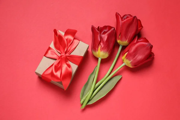 Schöne Geschenkschachtel Und Tulpen Auf Rotem Hintergrund Flache Lage — Stockfoto