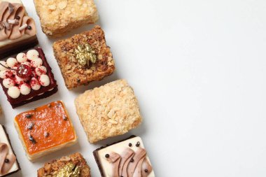 Farklı lezzetli pastaların parçaları beyaz masada, düz yerde. Metin için boşluk