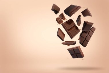 Kırık çikolata parçaları pembe bej arka plana düşüyor, metin için boşluk