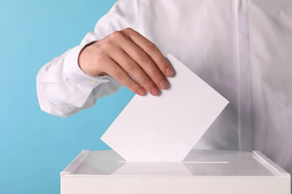 Mann Legt Seine Stimme Die Wahlurne Auf Hellblauem Hintergrund Nahaufnahme — Stockfoto