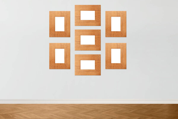 Blank wooden frames hanging on light gray wall. Mockup for design