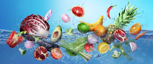 stock image Many fruits and vegetables falling into water against blue background