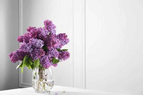 壁の近くの白いテーブルの花瓶の美しいライラックの花 テキストのためのスペース — ストック写真