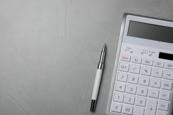 stock image Calculator and pen on grey table, top view. Space for text