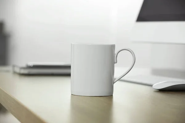 stock image White ceramic mug on wooden table at workplace. Mockup for design
