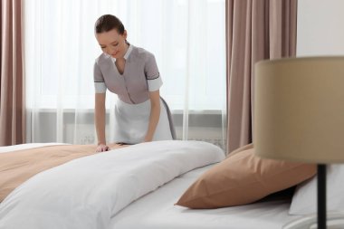 Genç hizmetçi otel odasında yatak yapma