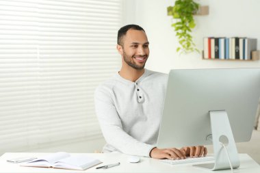 Odadaki masada bilgisayarda çalışan genç bir adam. Merkez Ofis