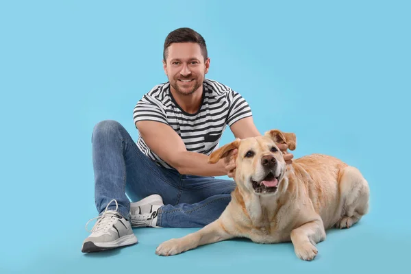 愛らしいラブラドールを持つ男ライトブルーの背景に犬を取得します 可愛いペット — ストック写真