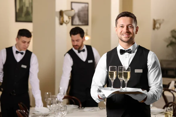 Stock image Butler holding tray with glasses of sparkling wine in restaurant. Space for text