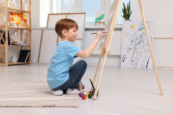 スタジオで絵を描く少年 キャンバスを保持するためにイーゼルを使用 — ストック写真