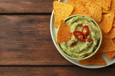 Bir kase lezzetli guacamole ve cips, ahşap masa, üst manzara. Metin için boşluk