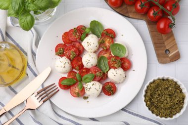 Lezzetli salata Caprese domatesli, mozzarella toplu ve fesleğenli beyaz fayanslı masada servis edilmiş, düz yatıyordu.