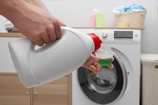 Man Hälla Tyg Mjukgörare Från Flaska Till Mössa Nära Tvättmaskin — Stockfoto