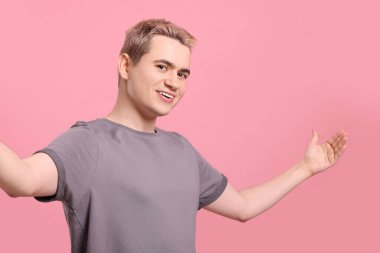 Pembe arka plana davet eden mutlu adam.