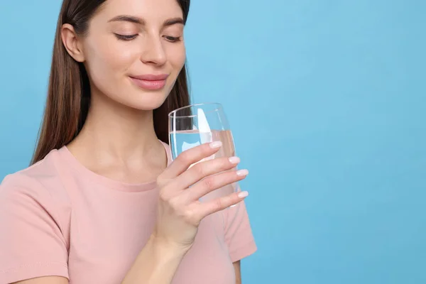 Healthy habit. Woman holding glass with fresh water on light blue background. Space for text