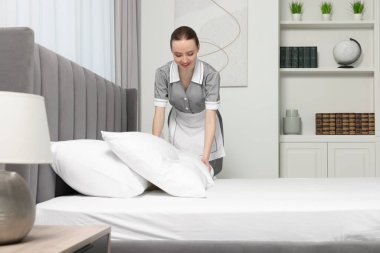 Genç hizmetçi otel odasında yatak yapma