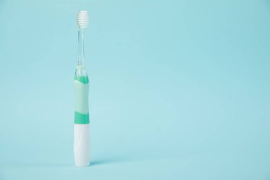 Açık mavi arkaplanda elektrikli diş fırçası, metin için boşluk