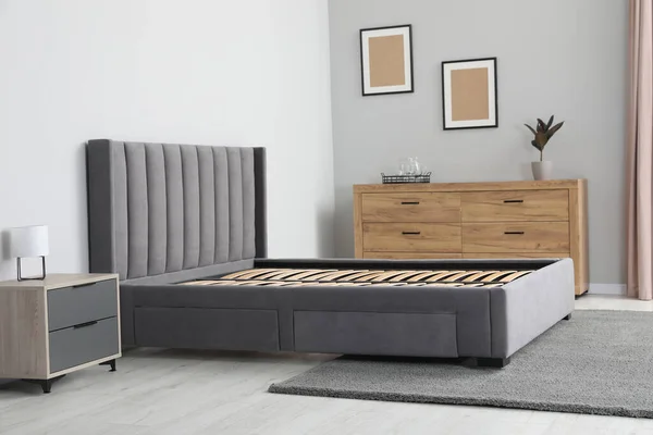Comfortable bed with storage space for bedding under slatted base in stylish room