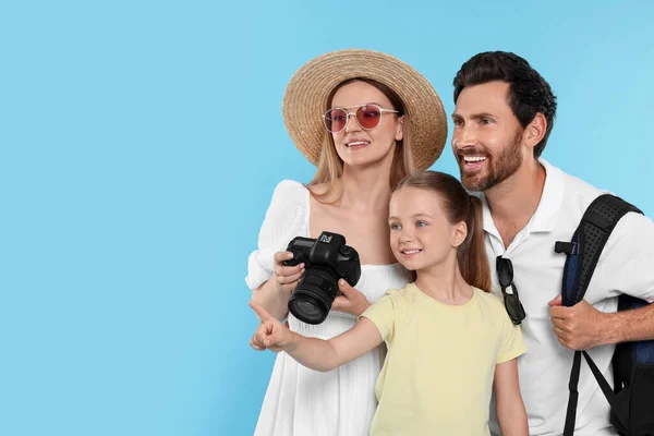 Happy family with camera on light blue background, space for text