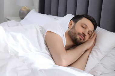 Evdeki yumuşak yatakta uyuyan yakışıklı adam.