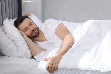 Evdeki yumuşak yatakta uyuyan yakışıklı adam.