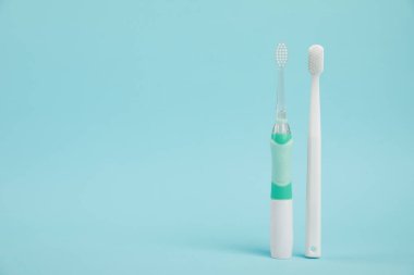 Açık mavi arkaplanda elektrik ve plastik diş fırçaları, metin için boşluk