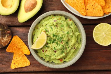 Bir kase lezzetli guacamole, limon ve cips ahşap masa, düz yatıyordu.