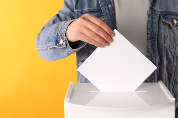 イエローバックグラウンドで投票ボックスに投票する男 クローズアップ — ストック写真